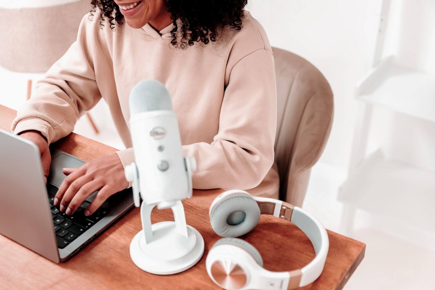 woman with hands on laptop microphone and headphones on desk working on her executive coaching services